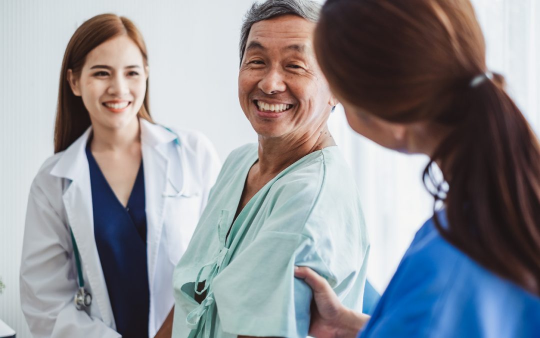 Asian female doctor and nurse encourage senior patient sitting on wheelchair at hospital