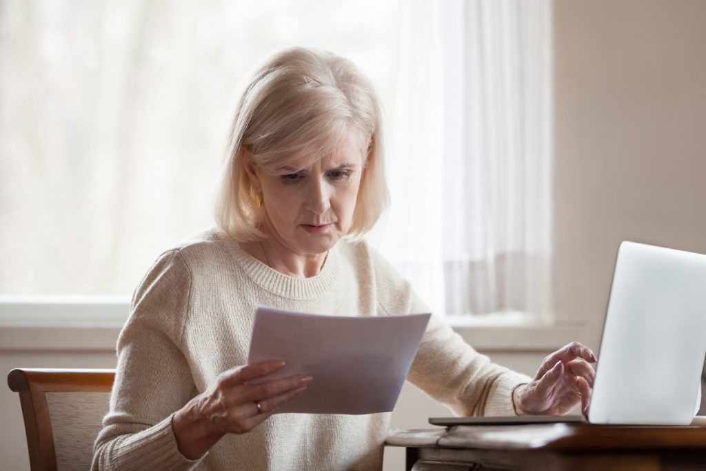 Serious frustrated middle aged senior woman worried reading bad news in paper letter document, stressed upset mature lady troubled with medical bills