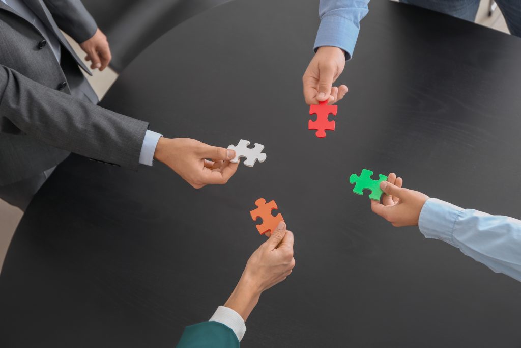 Business team assembling puzzle on dark table