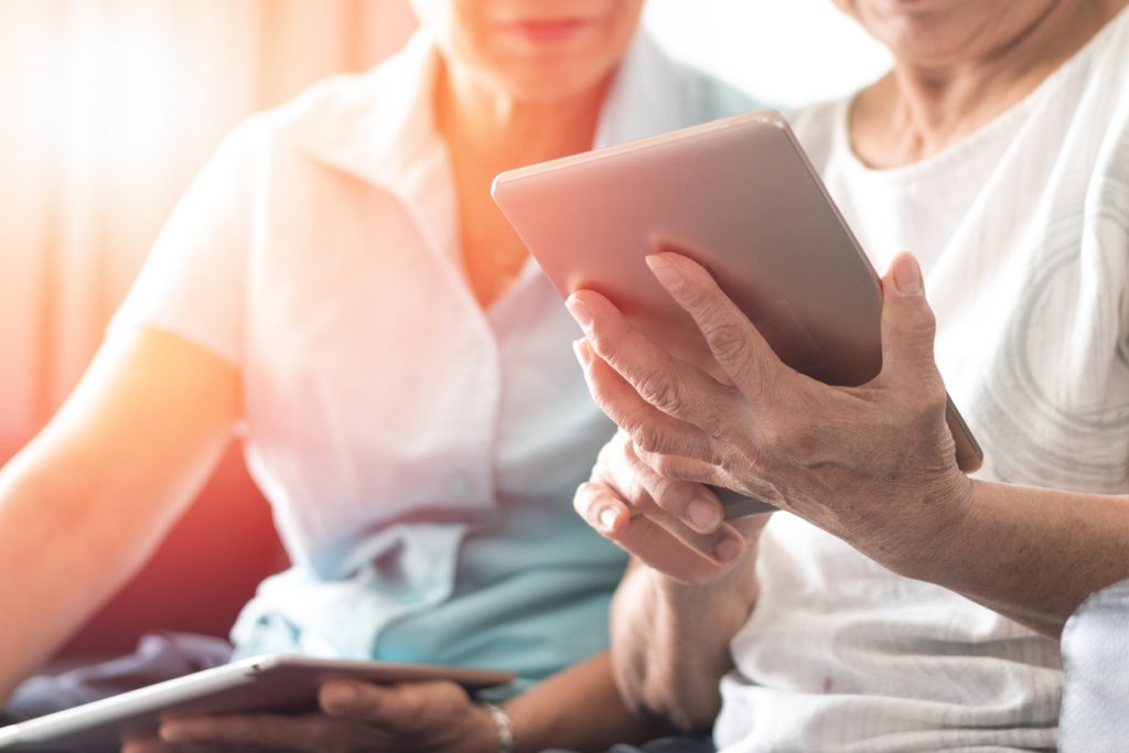 Happy elderly senior people society lifestyle with technology concept. Ageing Asia women using tablet and smartphone share social media together in wellbeing county home.