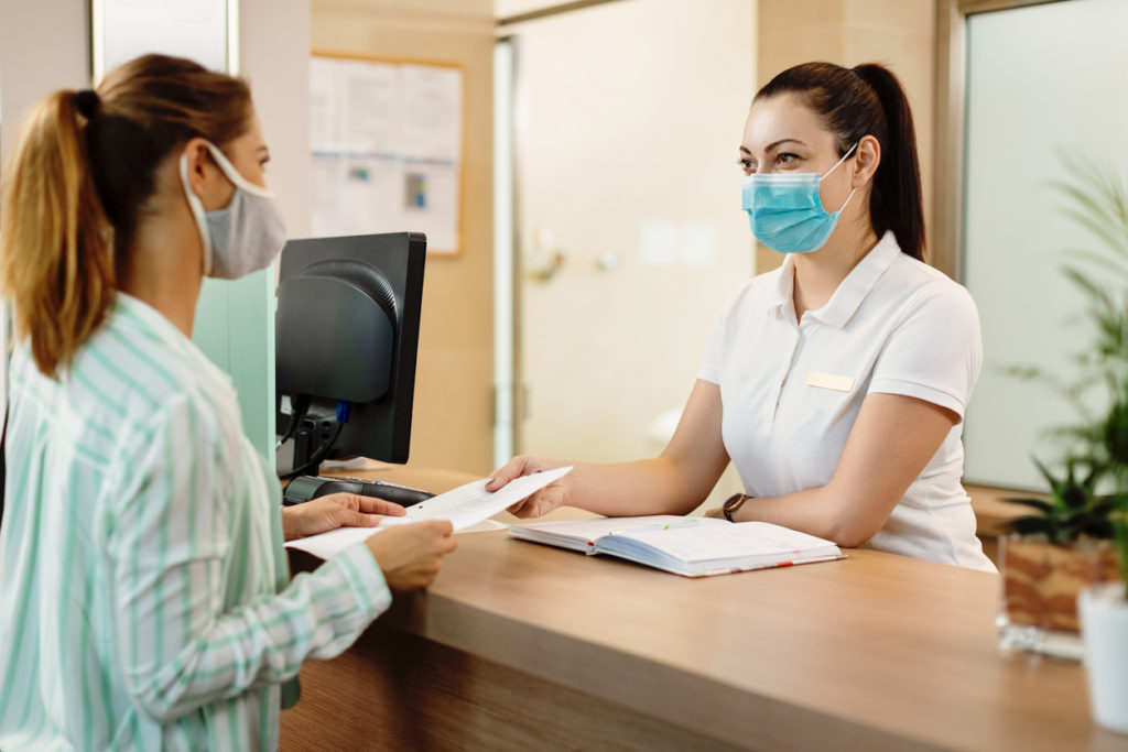 receptionist and her patient wearing face masks