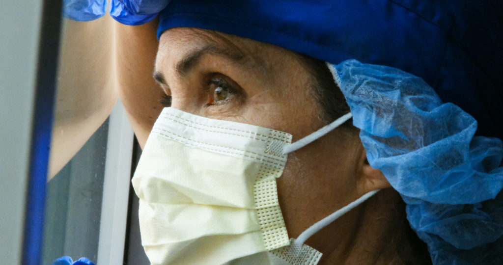 Overworked, female mature health care worker looking through a window