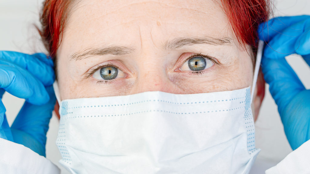 Close-up portrait of a nurse adjusting her protective surgical mask